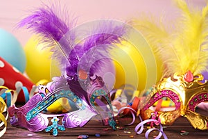 Beautiful carnival masks and party decor on wooden table, closeup