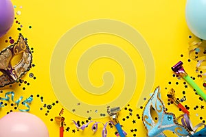 Beautiful carnival masks and party decor on yellow background, flat lay. Space for text