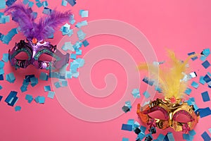 Beautiful carnival masks and shiny confetti on pink background, flat lay. Space for text