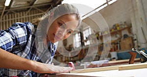 Beautiful carpenter blowing on wooden plank