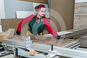 Beautiful carpenter making measurements of wooden plank