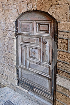 Beautiful carved wooden door in the stone wall of  very ancient stone building in the Old City of Jaffa in Israel