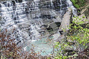 Beautiful cascading waterfall flowing over tiered rocks into swirling turquoise pool