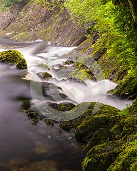 Beautiful cascading waterfall through a lush green landscape - Swallow Falls in North Wales