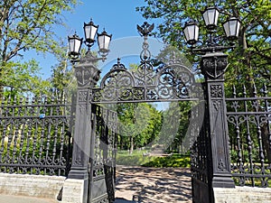 Beautiful cast-iron gates with lanterns and a lattice with decorations at the entrance to the Summer Garden of the city of