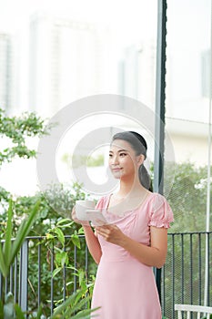 Beautiful casual asian woman vacationer standing outdoors and typing on her cell phone