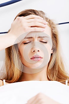 Beautiful casual caucasian woman lying in bed,touching her forehead.