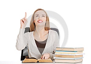 Beautiful casual student woman sitting by stack of books and poi