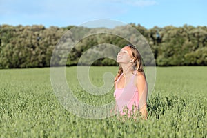 Beautiful casual woman breathing happy in a green meadow