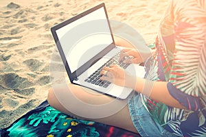 Beautiful casual woman with a laptop on the beach