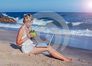 Beautiful casual woman with a laptop on the beach with the sea i