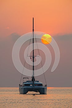 Beautiful catamaran sailing on the background of the sea sunrise