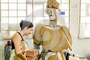 Beautiful Caucasian artist working on her sculpture in an atelier