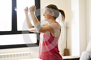 Beautiful caucasian athlete woman doing exercises with elastic band in living room at home