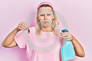 Beautiful caucasian blonde woman holding cockroach and pesticide sprayer depressed and worry for distress, crying angry and afraid