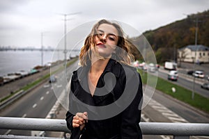 Beautiful Caucasian woman leaning on a bridge over the highway In Winter Time.