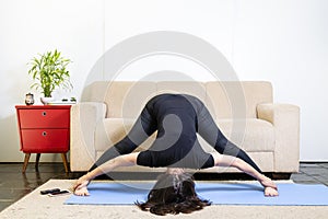 Beautiful caucasian brunette woman in black clothes on blue yoga