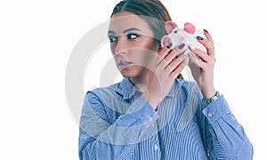 Beautiful Caucasian brunette woman listens to the sound of coinsin a piggy bank and dreams.
