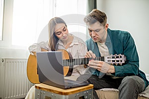 Beautiful caucasian couple watch lessons of playing guitar