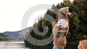 Beautiful Caucasian female girl standing near beautiful lake in mountains and throw a rock. slow mo