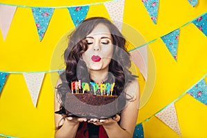 Beautiful caucasian girl blowing candles on her cake. Celebration and party. Having fun. Young pretty woman in red dress and birth