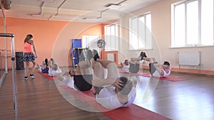 Beautiful caucasian girl coach shows men in a group doubles class how to perform exercises for endurance and weight loss