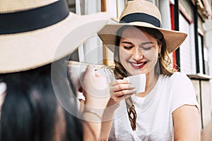 Beautiful caucasian girl drink an italian espresso coffee with her friend at the bar - trendy modern people portrait - young woman photo