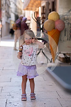 Beautiful Caucasian girl with ice cream on the street of an ancient city in Croatia