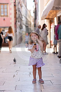 Beautiful Caucasian girl with ice cream on the street of an ancient city in Croatia