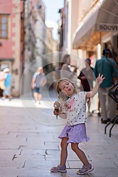 Beautiful Caucasian girl with ice cream on the street of an ancient city in Croatia