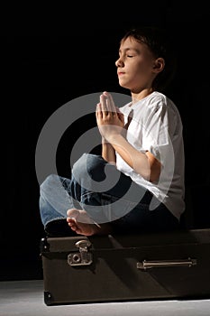 Beautiful Caucasian lad sitting on a suitcase