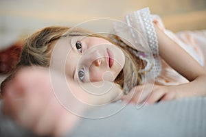 Beautiful caucasian little girl lying on bed indoors home room relaxing