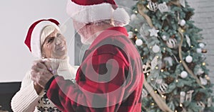 Beautiful caucasian mature woman dancing with husband on New Year's eve at home. Woman looking at man with love