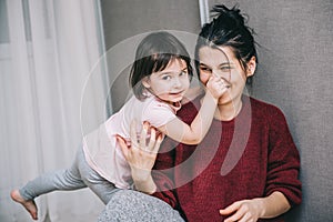 Beautiful Caucasian mother and her child playing together at home. Girl and mom in casual sitting on th carpet. Happy mum and kid