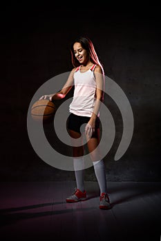Beautiful caucasian teen woman in sportswear playing basketball . Sport concept isolated on black background.