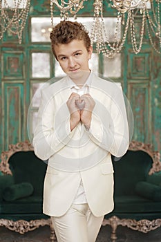Beautiful caucasian teenager boy shows heart love symbol by arms palms alone in white clothes.