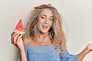 Beautiful caucasian teenager girl eating sweet watermelon slice celebrating achievement with happy smile and winner expression