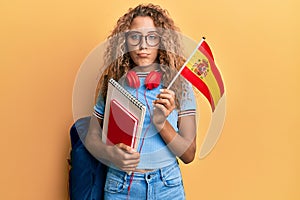 Beautiful caucasian teenager girl exchange student holding spanish flag depressed and worry for distress, crying angry and afraid