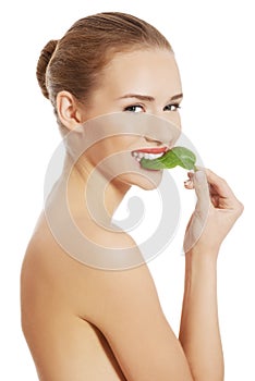 Beautiful caucasian topless woman with one green leaf.