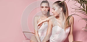 Beautiful caucasian twins female models on pink background.