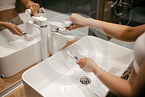 Beautiful caucasian woman in a bathroom wetting a toothbrush. Close shot of the hands.