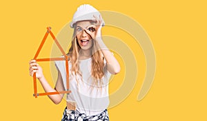 Beautiful caucasian woman with blonde hair wearing architect hardhat and holding tools smiling happy doing ok sign with hand on