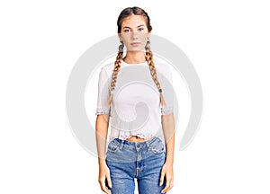 Beautiful caucasian woman with blonde hair wearing braids and white tshirt with serious expression on face