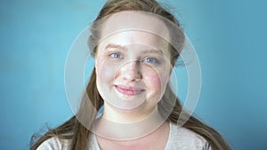 Beautiful caucasian woman on blue background smiling camera, youth happiness