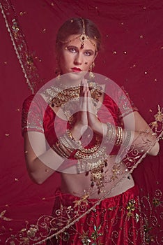 Beautiful caucasian woman dressed in Indian bridal Sari along with specific jewelry: Mangalsutra, Thaali, Maang Tikka, Choora, Nat