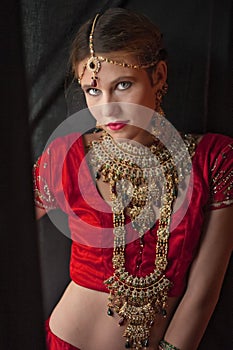 Beautiful caucasian woman dressed in Indian bridal Sari along with specific jewelry: Mangalsutra, Thaali, Maang Tikka, Choora, Nat