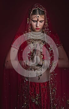 Beautiful caucasian woman dressed in Indian bridal Sari along with specific jewelry: Mangalsutra, Thaali, Maang Tikka, Choora, Nat
