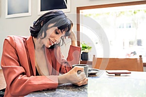 Beautiful Caucasian woman drinking coffee in cafe restaurant alone. The girl holding cup of hot coffee sitting on table next to wi