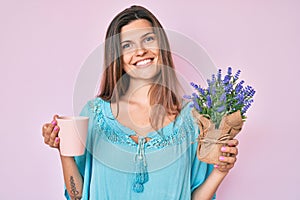 Beautiful caucasian woman drinking a cup of infused lavender smiling with a happy and cool smile on face