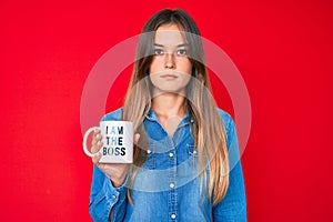Beautiful caucasian woman drinking from i am the boss coffee cup thinking attitude and sober expression looking self confident